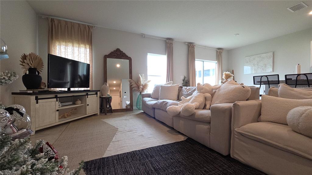 A living room features a large beige sectional sofa, a television console, and a floor mirror — 1427 MADISON CIRCLE, HAINES CITY, FL