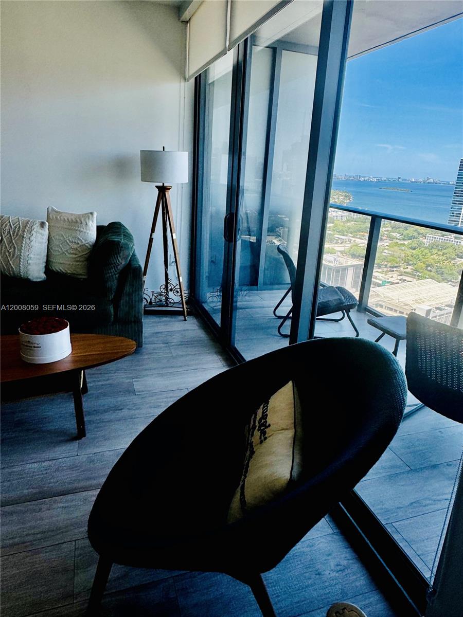 A living room features a dark sofa, a tripod floor lamp, and a balcony view — 121 NE 34th St # 2705, Miami FL 33137, MIAMI, FL