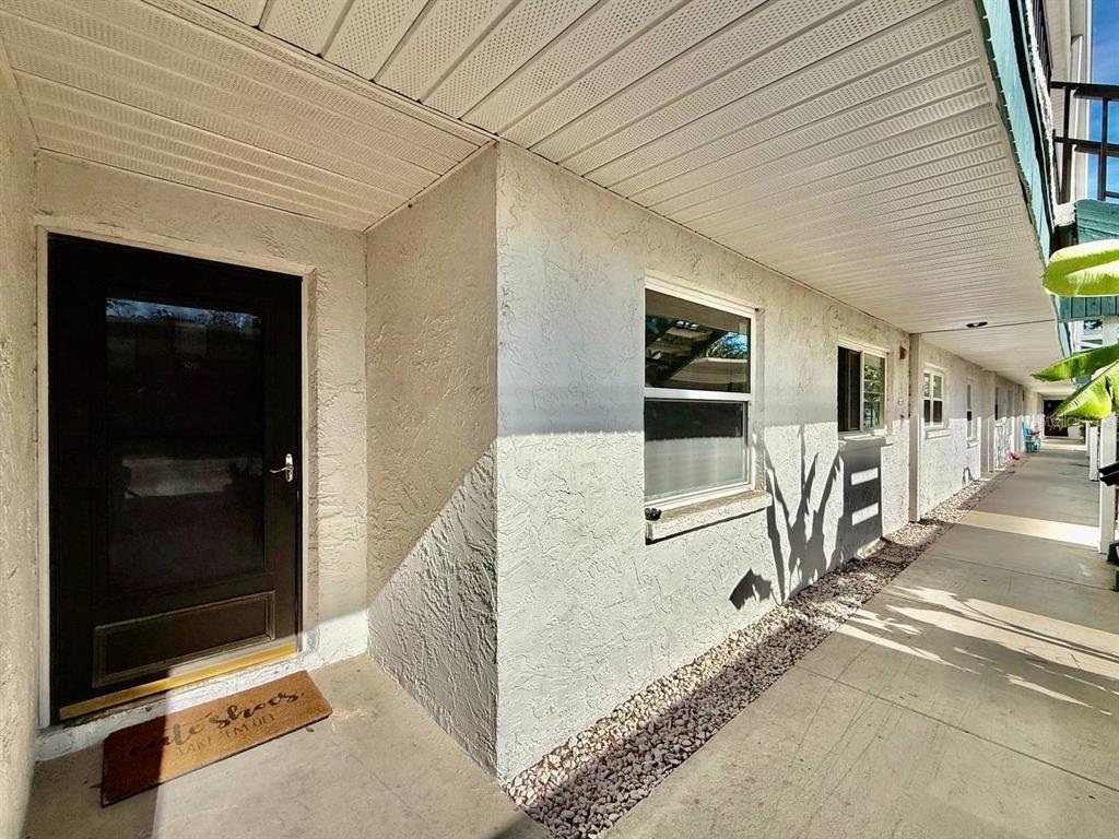 An exterior view of a ground-level apartment entrance with a black door and concrete walkway — 7560 92ND STREET UNIT 102B, SEMINOLE, FL