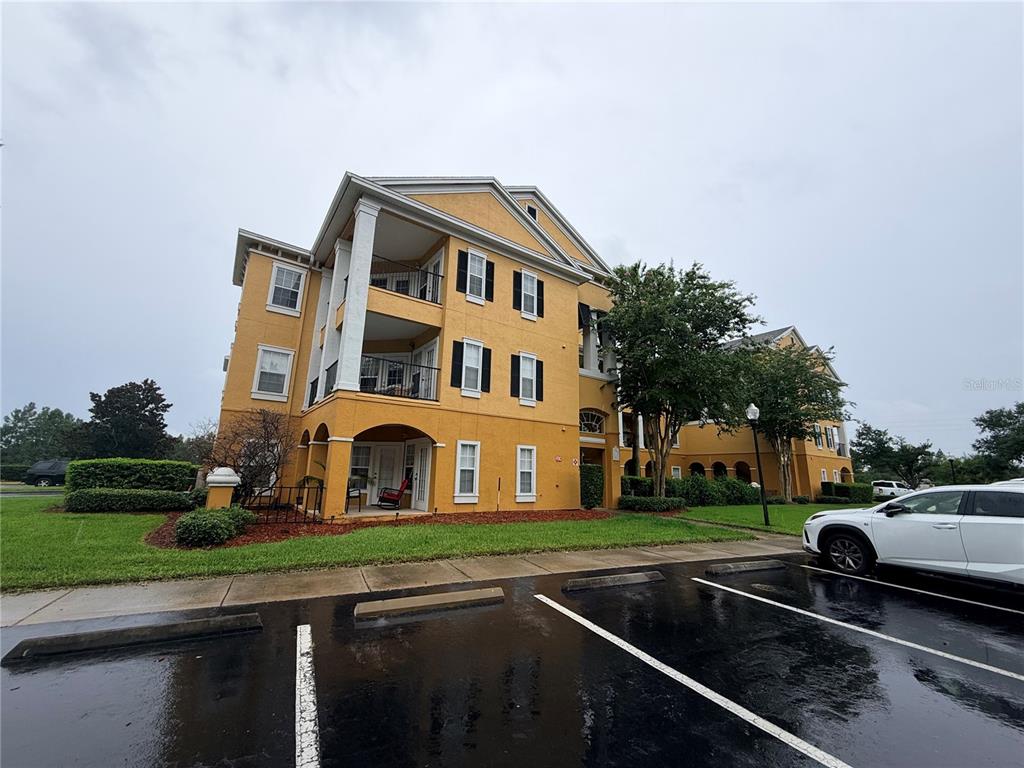 A multi-story yellow apartment building with balconies and a parking lot in the foreground — 3751 CONROY ROAD UNIT 2315, ORLANDO, FL