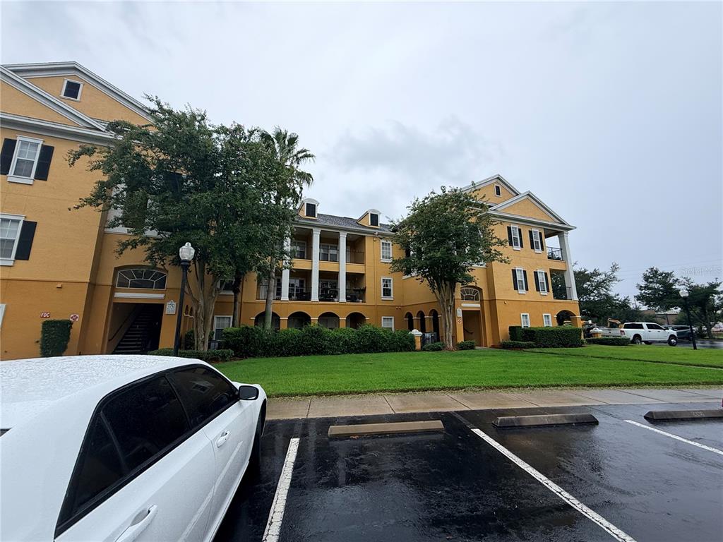 A three-story yellow apartment building with balconies and a parking lot in the foreground — 3751 CONROY ROAD UNIT 2315, ORLANDO, FL