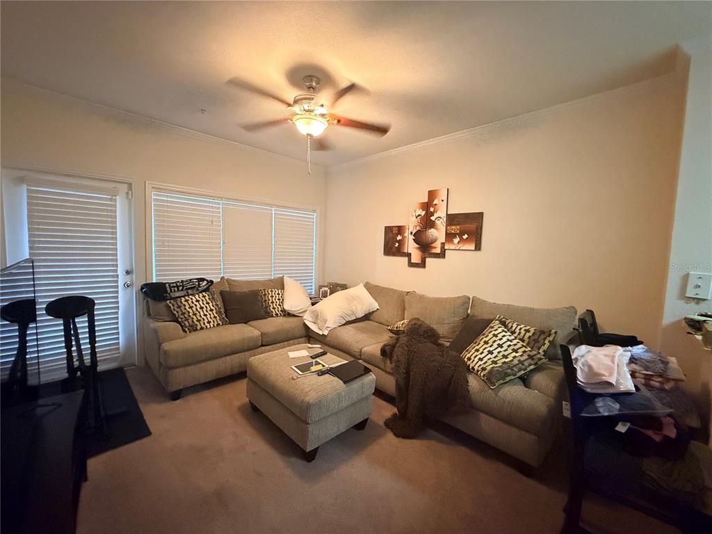 A living room features a beige sectional sofa, a matching ottoman, and a ceiling fan — 3751 CONROY ROAD UNIT 2315, ORLANDO, FL