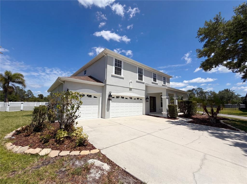 A two-story house with a light gray exterior, a three-car garage, and a concrete driveway — 1714 BOTTLEBRUSH WAY, NORTH PORT, FL