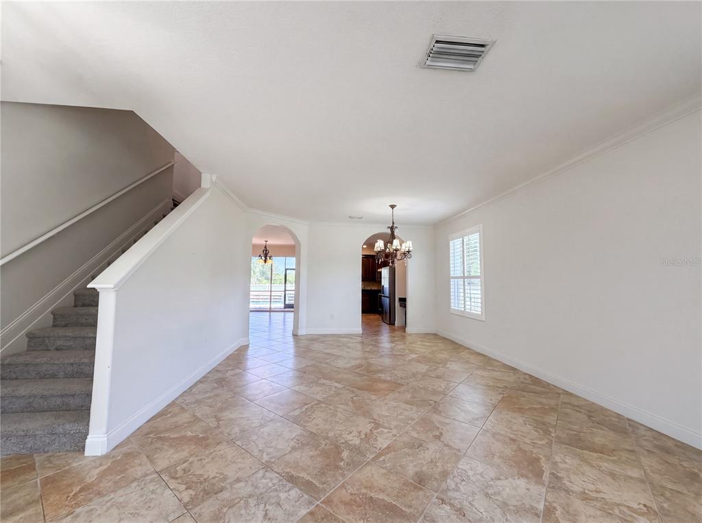 A tiled room features a staircase on the left and two arched doorways leading beyond — 1714 BOTTLEBRUSH WAY, NORTH PORT, FL