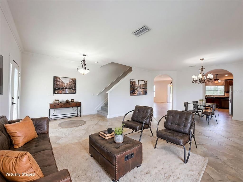 A living room with tile floors, a staircase, and leather furniture is shown in this rendering — 1714 BOTTLEBRUSH WAY, NORTH PORT, FL