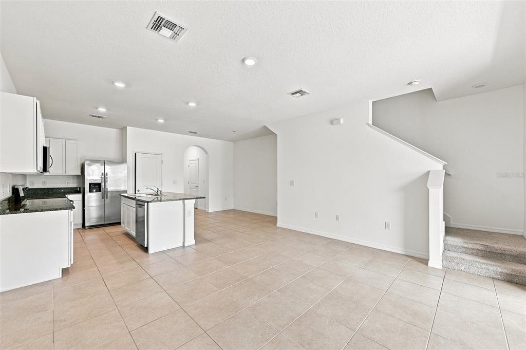 A kitchen with white cabinets and a center island opens into a tiled living area — 3144 PLEASANT WILLOW COURT, BRANDON, FL