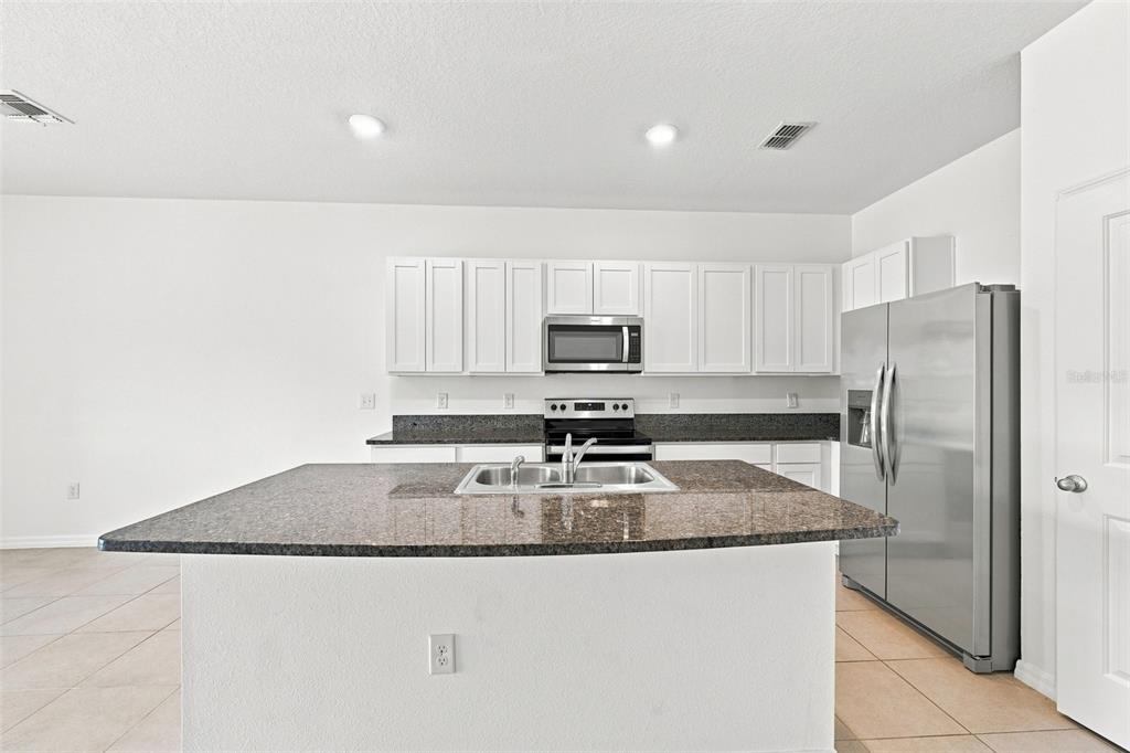 A kitchen features white cabinets, granite countertops, a central island, and stainless steel appliances — 3144 PLEASANT WILLOW COURT, BRANDON, FL
