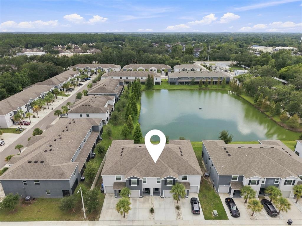 An aerial view shows a multi-unit townhouse complex situated next to a large pond — 3144 PLEASANT WILLOW COURT, BRANDON, FL