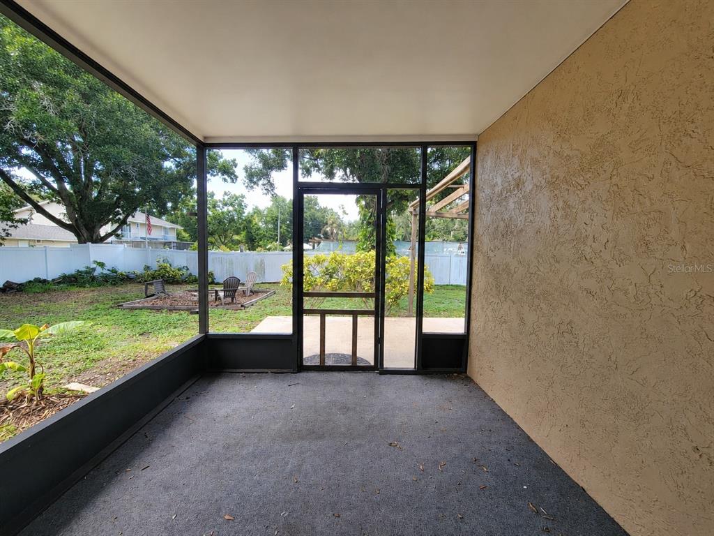 A screened-in porch with a concrete floor overlooks a backyard with a white fence — 5967 102ND AVENUE N, PINELLAS PARK, FL