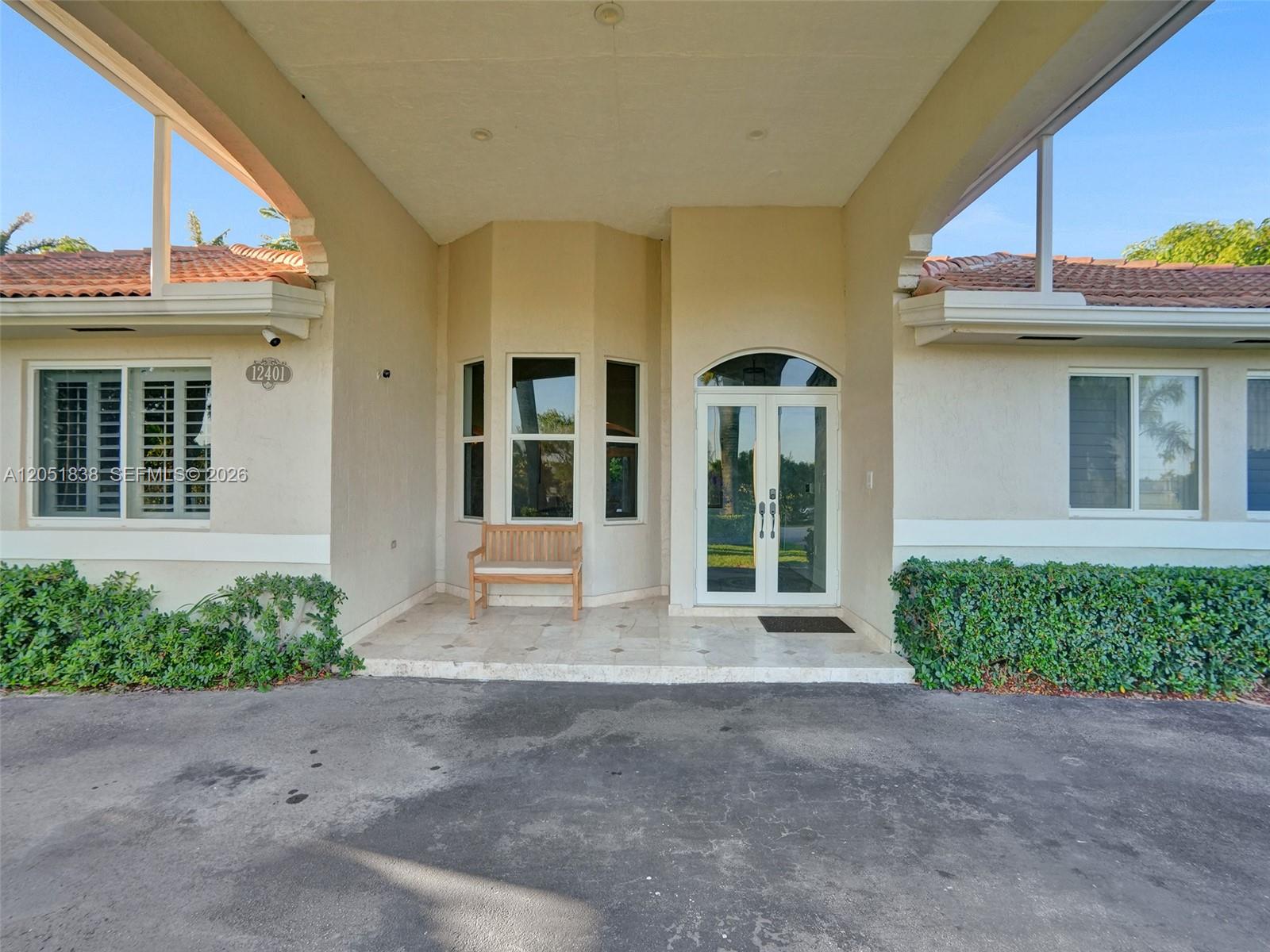 The exterior of a house features a covered entryway, a wooden bench, and double glass doors — 12401 SW 77th St # 12401, Miami FL 33183, MIAMI, FL