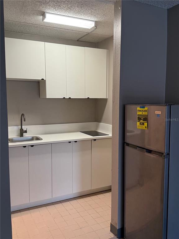 A small kitchenette features white cabinets, a stainless steel sink, a cooktop, and a refrigerator — 5020 W IRLO BRONSON MEMORIAL HIGHWAY UNIT 262, KISSIMMEE, FL