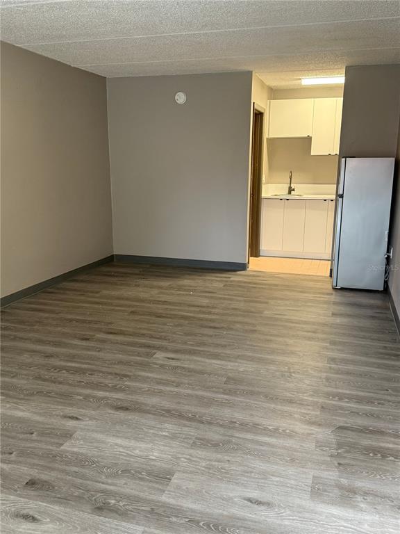 A room with wood-look flooring leads to a small kitchen area with white cabinets — 5020 W IRLO BRONSON MEMORIAL HIGHWAY UNIT 262, KISSIMMEE, FL