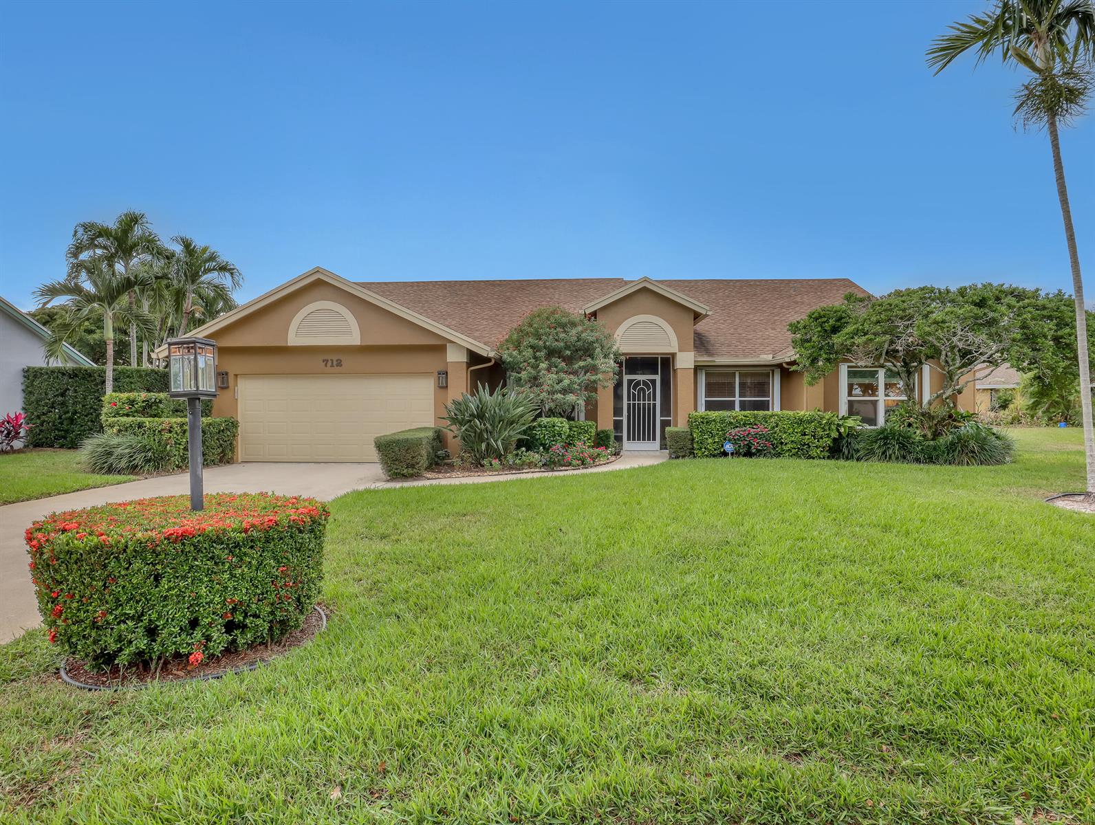 A single-story house with a tan exterior, a two-car garage, and a landscaped front yard — 712 Golf Court, Delray Beach FL 33445, DELRAY BEACH, FL