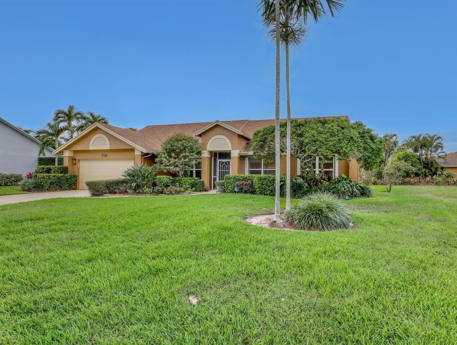 A single-story tan house with a two-car garage and palm trees in the front yard — 712 Golf Court, Delray Beach FL 33445, DELRAY BEACH, FL