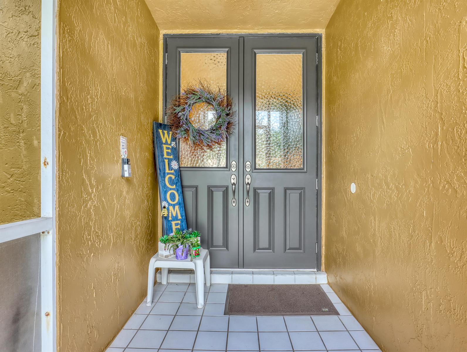 A front entryway features double gray doors, a welcome sign, and a small white stool — 712 Golf Court, Delray Beach FL 33445, DELRAY BEACH, FL