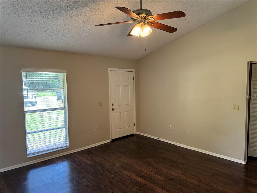 A living room features dark wood flooring, a ceiling fan, a window, and an exterior door — 10039 MASSEY STREET, ORLANDO, FL