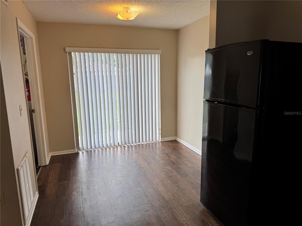 A dining area features dark wood-look flooring, a black refrigerator, and sliding glass patio doors — 10039 MASSEY STREET, ORLANDO, FL