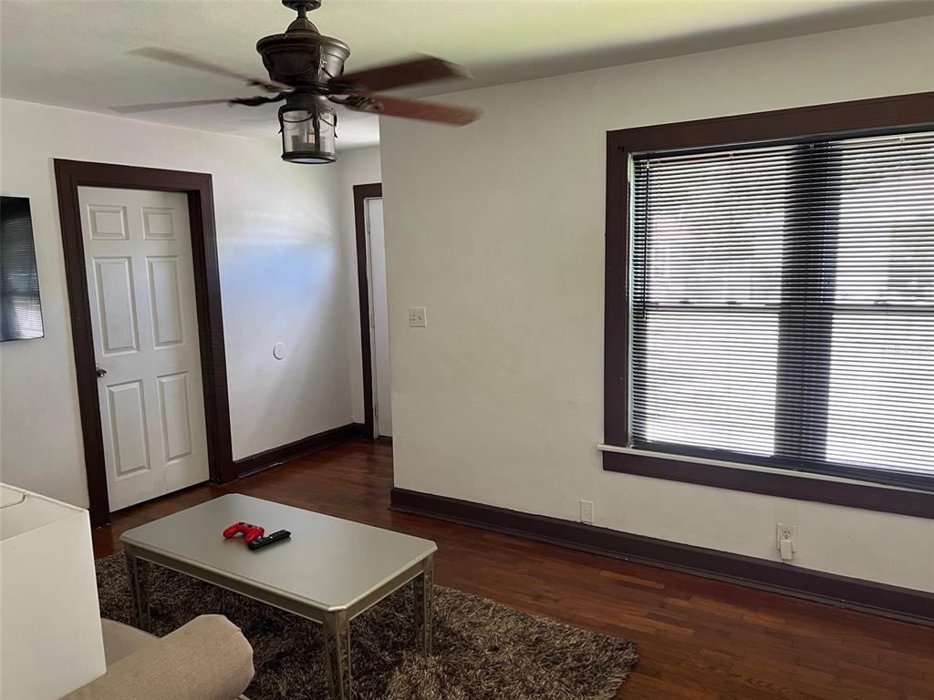 A living room features dark wood trim, hardwood floors, a ceiling fan, and a window — 2734 53RD AVENUE N, ST PETERSBURG, FL