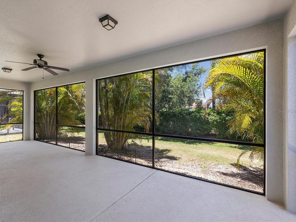 A covered patio with a concrete floor, ceiling fan, and large screened-in windows — 740 ROSEMARY CIRCLE, BRADENTON, FL