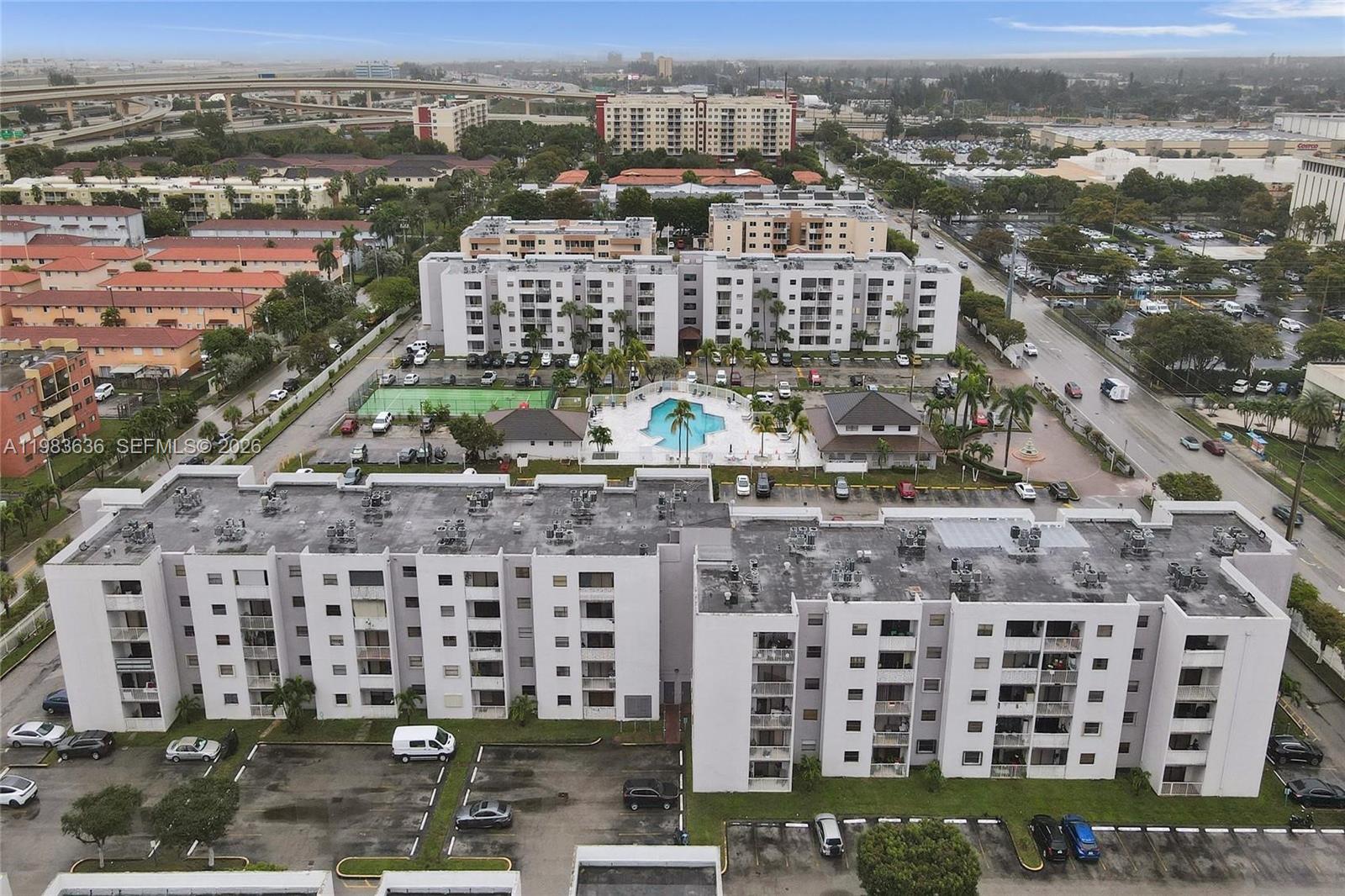An aerial view shows multiple apartment buildings with a central pool and tennis court — 8145 NW 7th St # 315, Miami FL 33126, MIAMI, FL
