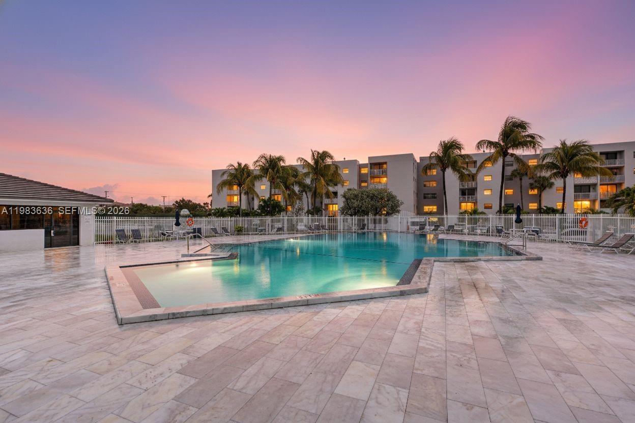 A swimming pool sits on a stone patio in front of a multi-story apartment building — 8145 NW 7th St # 315, Miami FL 33126, MIAMI, FL