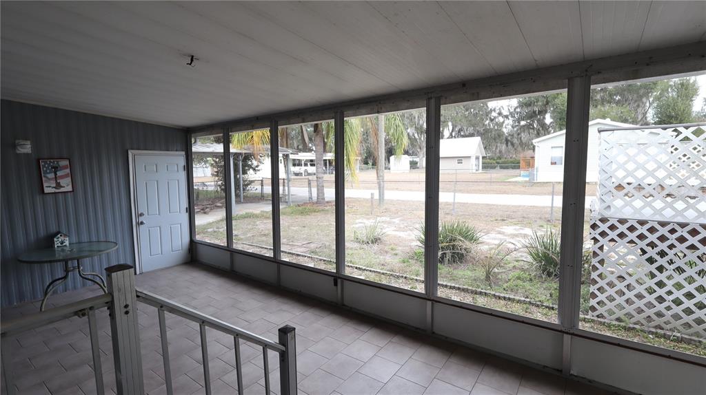 A wooden deck with white lattice railings sits in a grassy backyard next to a house — 1158 CR 439, LAKE PANASOFFKEE, FL