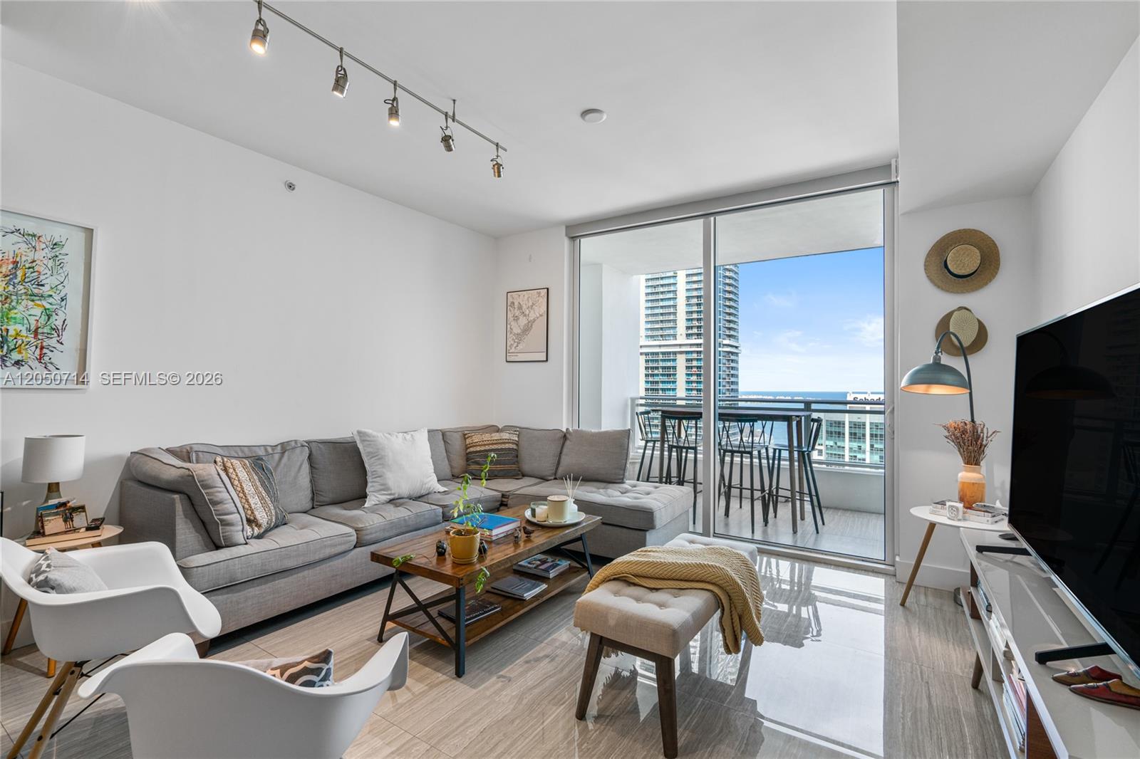 A modern living room features a gray sectional sofa, a coffee table, and a balcony view — 1080 Brickell Ave # 4102, Miami FL 33131, MIAMI, FL