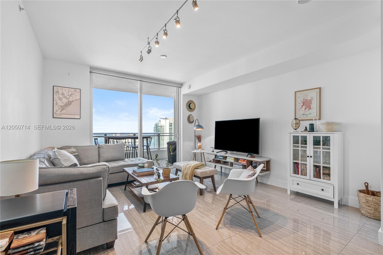A modern living room features a gray sectional sofa, white chairs, and a balcony view — 1080 Brickell Ave # 4102, Miami FL 33131, MIAMI, FL