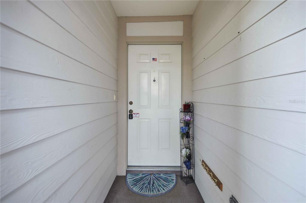 A white front door is centered between two light-colored horizontal siding walls — 3925 NE 22ND STREET, OCALA, FL
