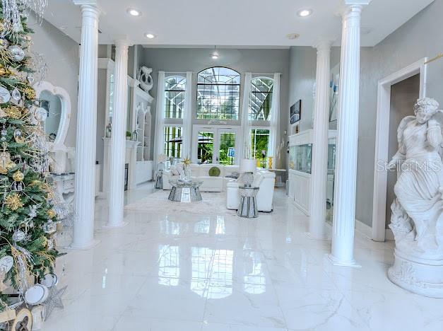 A bright, open-concept living room features white marble floors, classical columns, and large arched windows — 6823 NW 52ND LANE, GAINESVILLE, FL