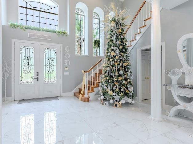 A grand foyer features white marble floors, a tall Christmas tree, and a staircase — 6823 NW 52ND LANE, GAINESVILLE, FL