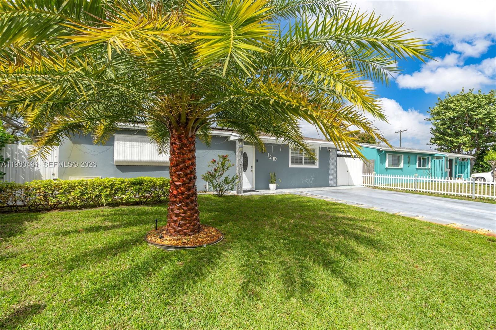 A gray house with a palm tree in the front yard and a white fence — 1210 N 71st Ave, Hollywood FL 33024, HOLLYWOOD, FL