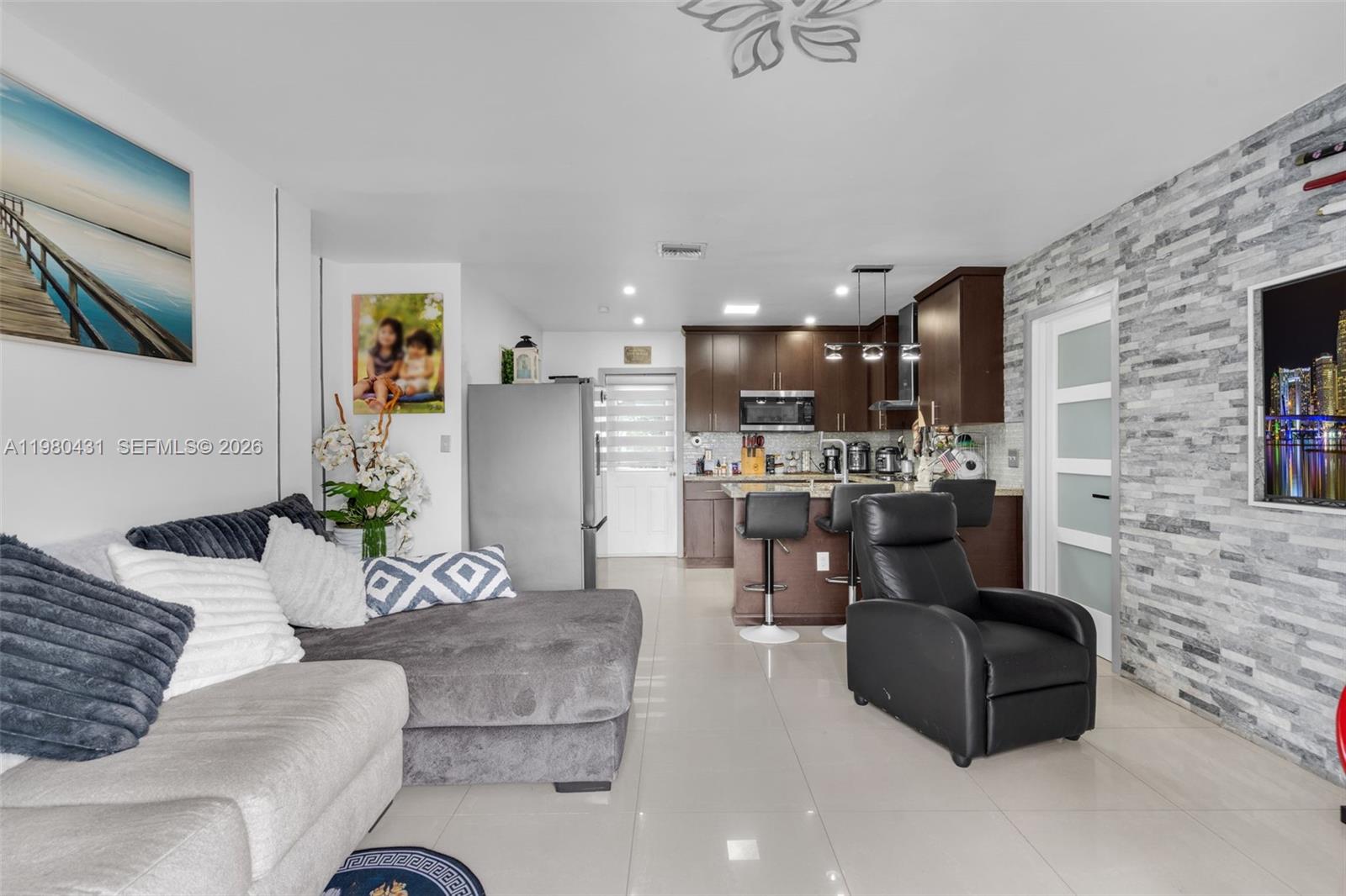 A living room with a gray sectional sofa and a kitchen with dark wood cabinets — 1210 N 71st Ave, Hollywood FL 33024, HOLLYWOOD, FL