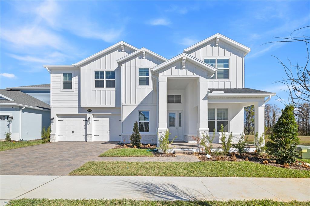 A two-story white house with a front porch, attached garage, and vertical siding — 16788 MUSKGRASS DRIVE, WINTER GARDEN, FL