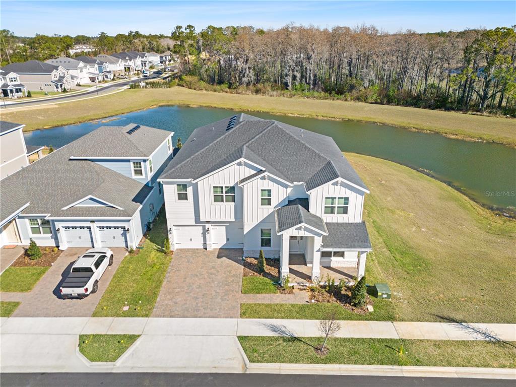 An aerial view shows a two-story white house with a paved driveway and pond view — 16788 MUSKGRASS DRIVE, WINTER GARDEN, FL