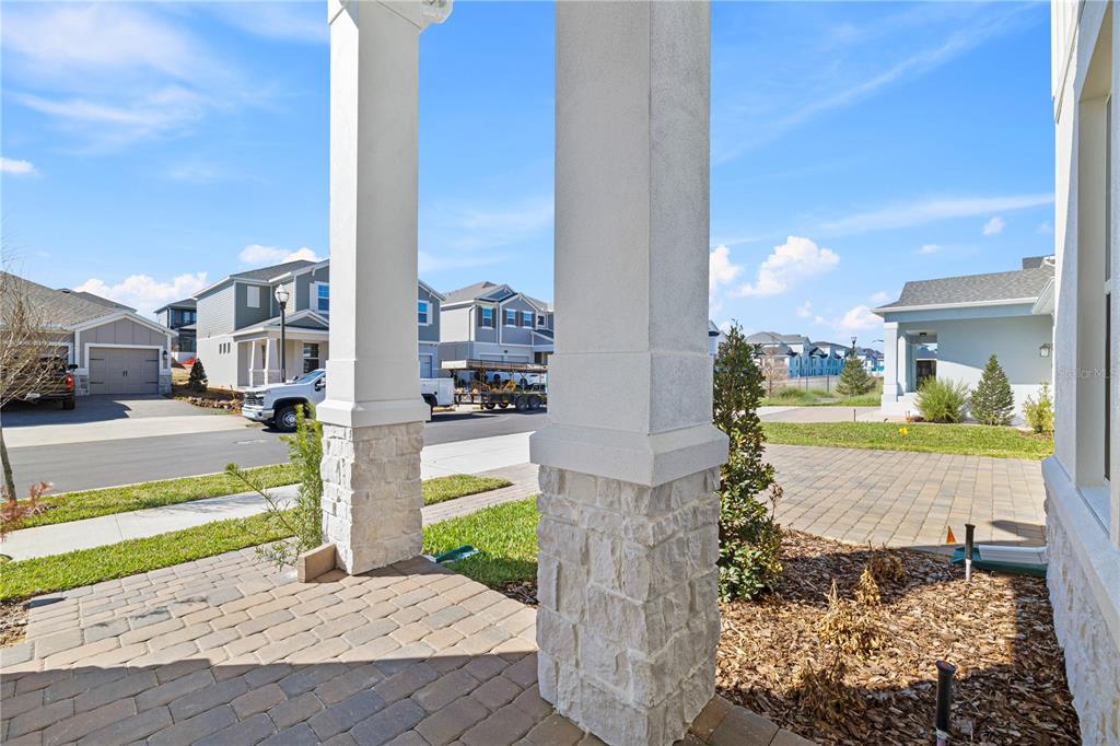 A view from a covered porch featuring two stone-based columns overlooking a suburban street — 16788 MUSKGRASS DRIVE, WINTER GARDEN, FL