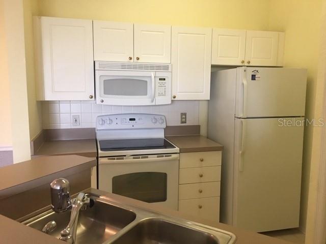 A kitchen features white cabinets, a white stove, a microwave, and a white refrigerator — 5180 NORTHRIDGE ROAD UNIT 308, SARASOTA, FL