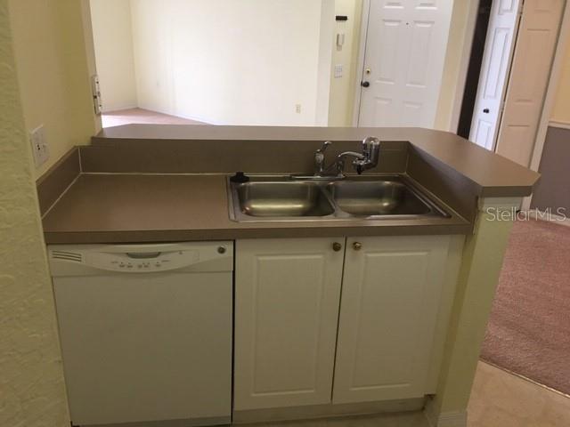 A kitchen sink and dishwasher are set into a countertop with light-colored cabinets — 5180 NORTHRIDGE ROAD UNIT 308, SARASOTA, FL