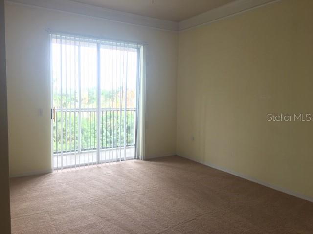An empty room with beige carpet, pale yellow walls, and a sliding glass door to a balcony — 5180 NORTHRIDGE ROAD UNIT 308, SARASOTA, FL