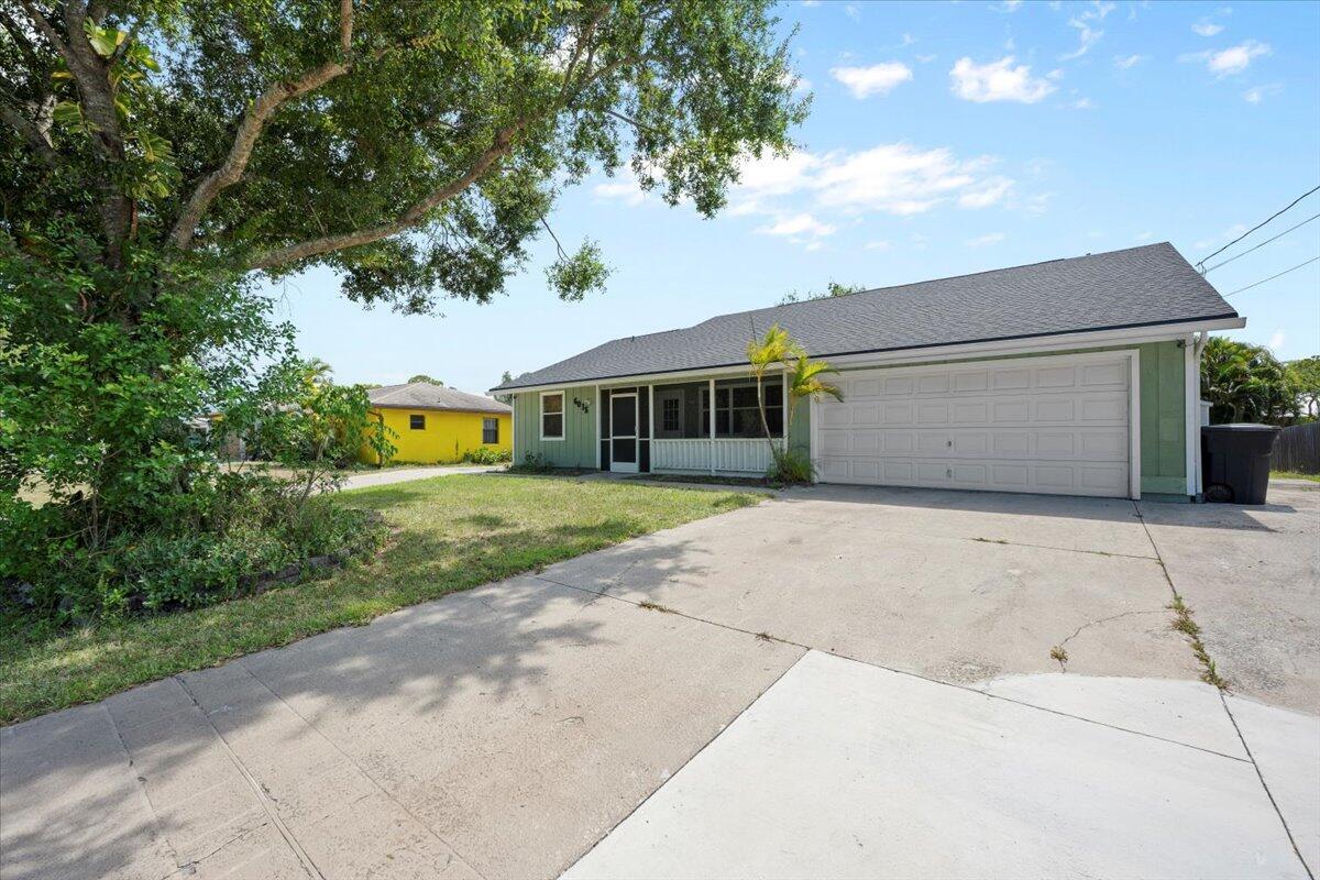 A single-story house with a green exterior, a two-car garage, and a screened front porch — 6015 Raintree Trl, Fort Pierce FL 34982, FORT PIERCE, FL