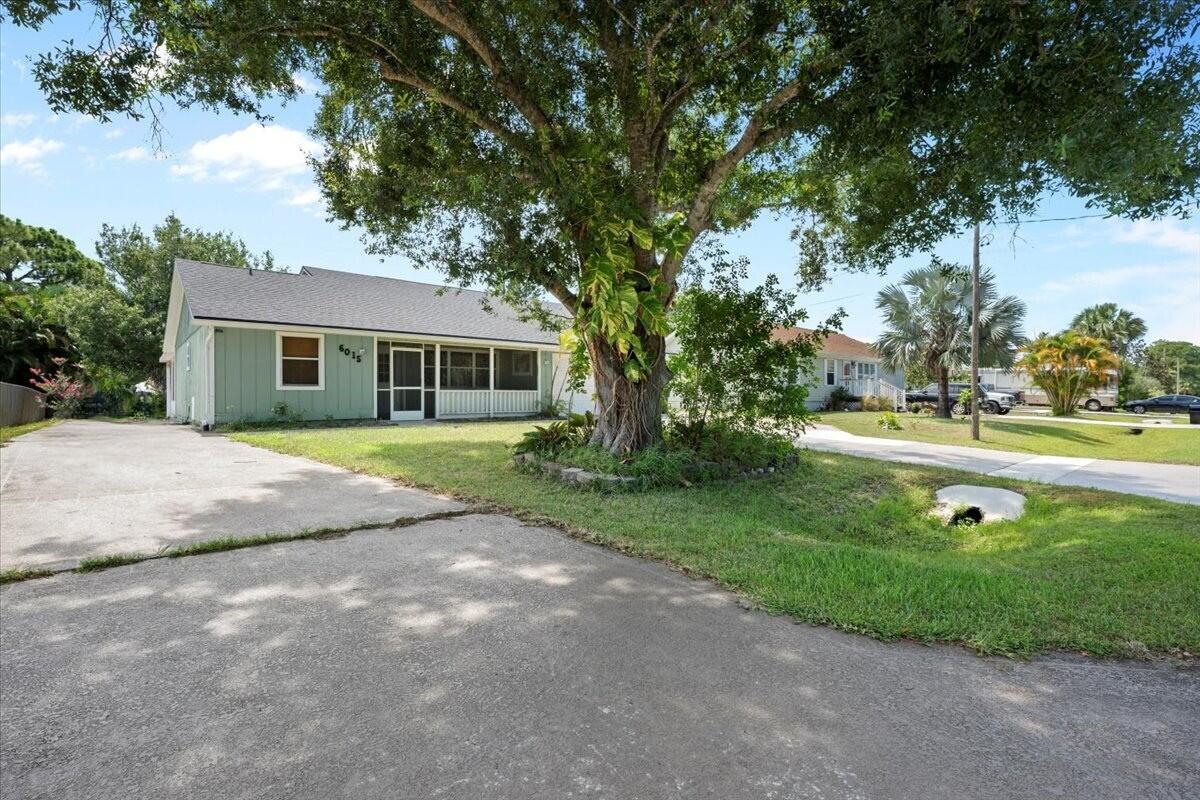 A light green single-story house with a large tree in the front yard — 6015 Raintree Trl, Fort Pierce FL 34982, FORT PIERCE, FL