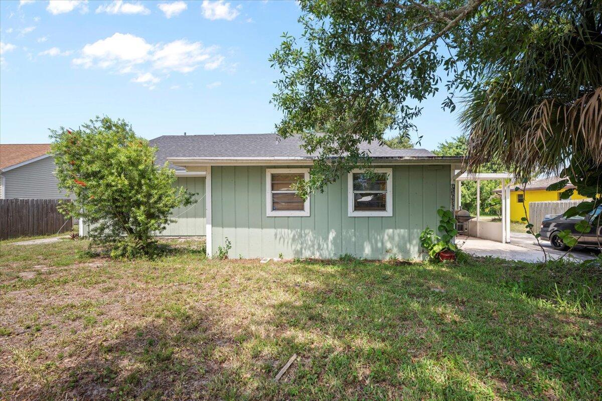 The exterior of a light green house features two windows and a covered side patio — 6015 Raintree Trl, Fort Pierce FL 34982, FORT PIERCE, FL