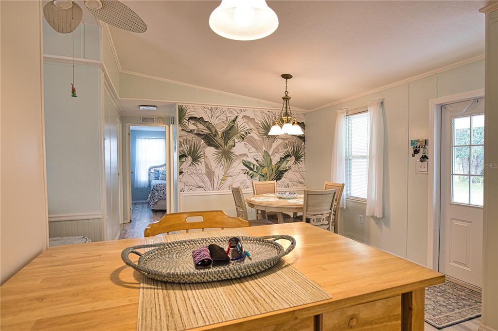 A dining area features a round table, tropical wallpaper, and a wooden kitchen island — 618 IGLESIA DRIVE, NORTH PORT, FL