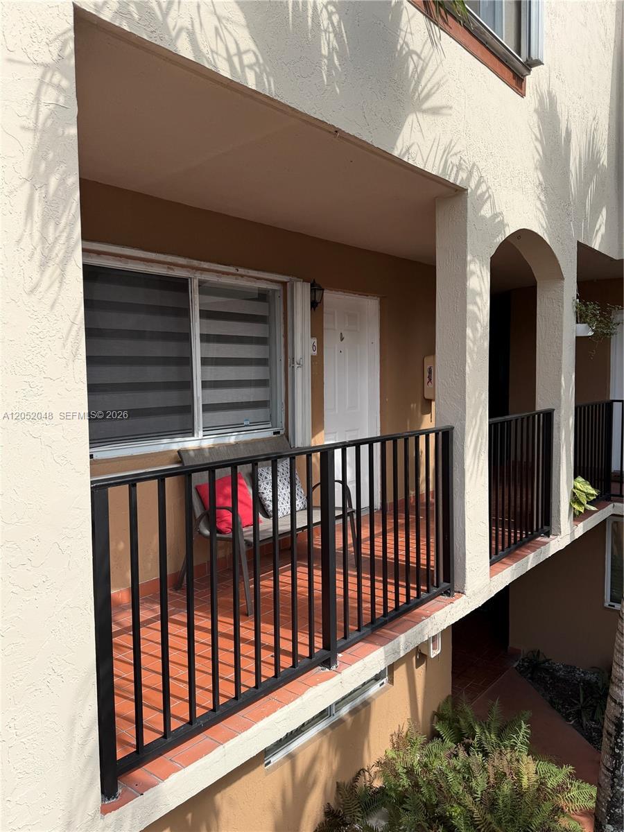 An exterior view of a balcony with a bench, a window, and a white door — 551 NW 82nd Ave # 516, Miami FL 33126, MIAMI, FL