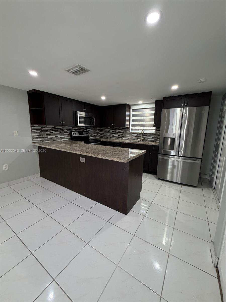 A kitchen features dark wood cabinets, granite countertops, stainless steel appliances, and white tile flooring — 551 NW 82nd Ave # 516, Miami FL 33126, MIAMI, FL