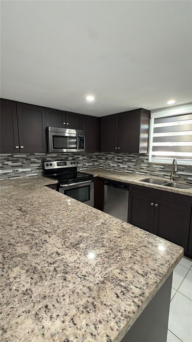 A kitchen features dark wood cabinets, granite countertops, stainless steel appliances, and a tiled backsplash — 551 NW 82nd Ave # 516, Miami FL 33126, MIAMI, FL