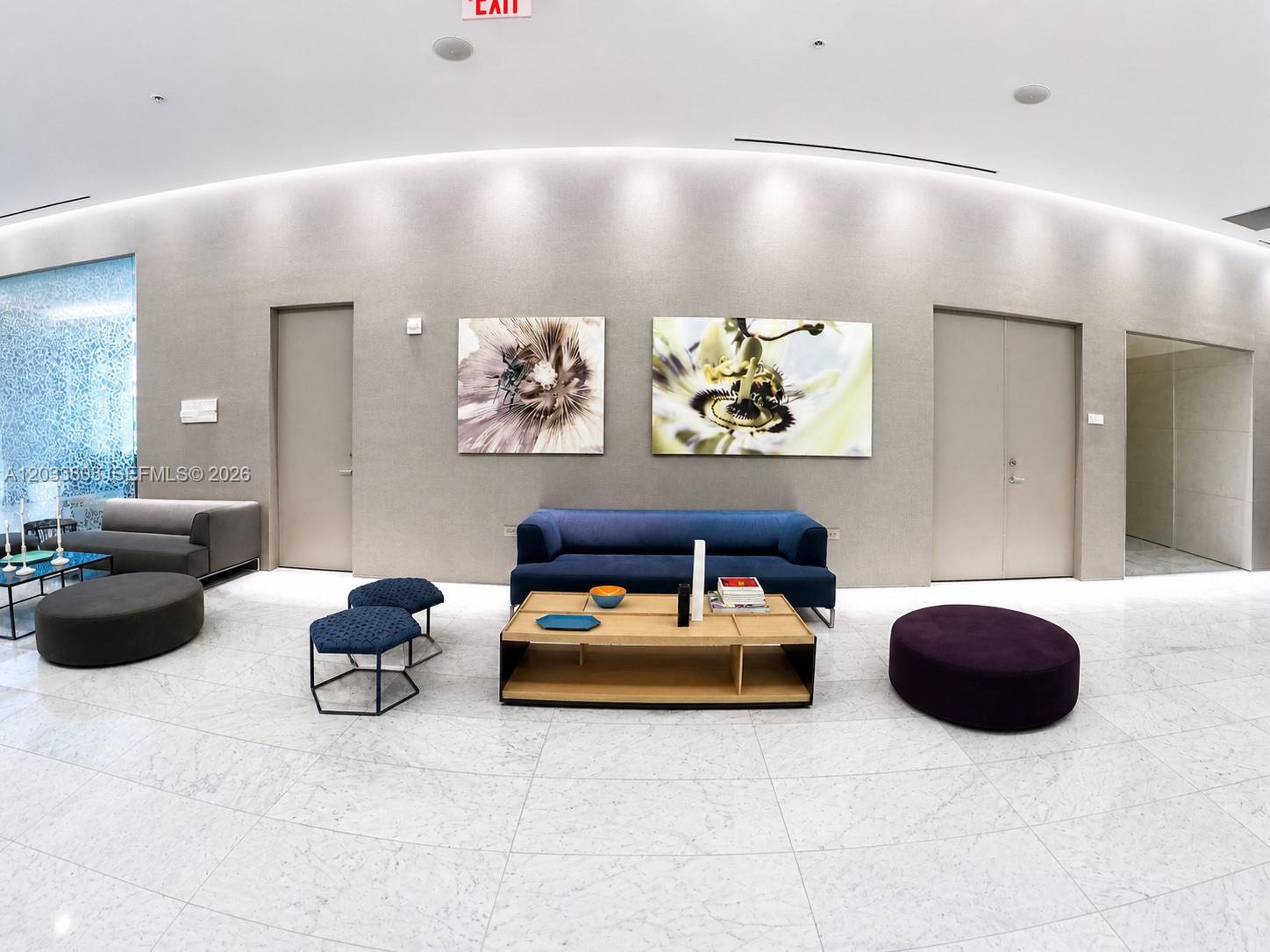 A modern lobby features a blue sofa, coffee table, and abstract floral wall art — 88 SW 7th St # 2206, Miami FL 33130, MIAMI, FL