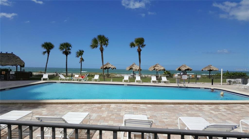 A rectangular swimming pool sits on a paved deck overlooking the ocean and beach — 1480 GULF BOULEVARD UNIT 106, CLEARWATER BEACH, FL