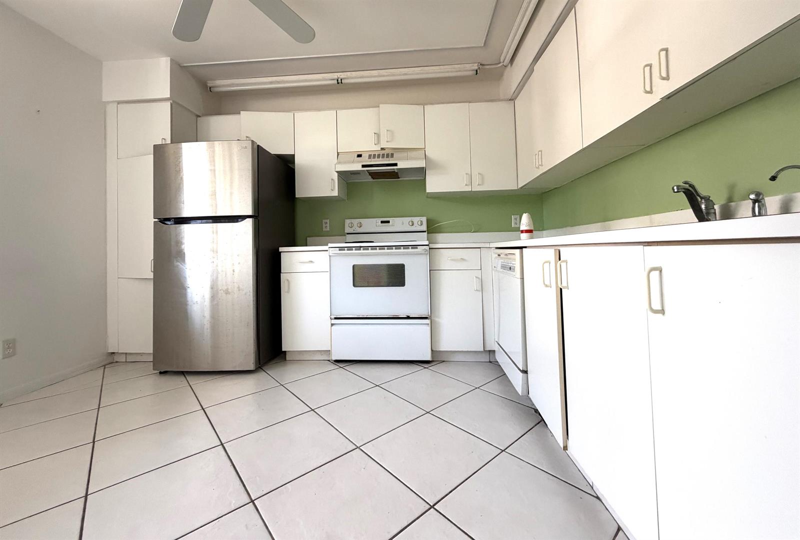 A kitchen features white cabinets, stainless steel refrigerator, white appliances, and green backsplash tile — 10382 NW 24th Place, Sunrise FL 33322, SUNRISE, FL