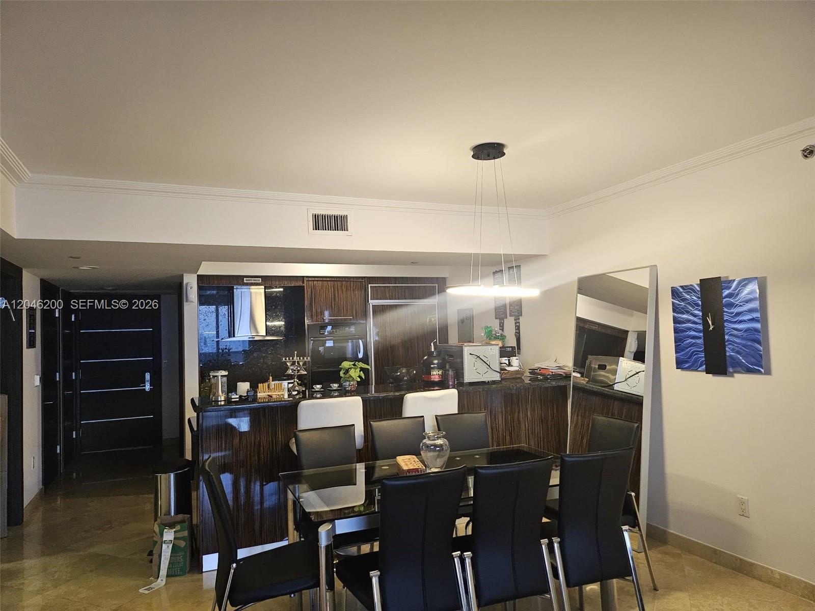 A dining area with a glass table and black chairs sits before a modern kitchen — 1830 S Ocean Dr # 2403, Hallandale Beach FL 33009, HALLANDALE BEACH, FL
